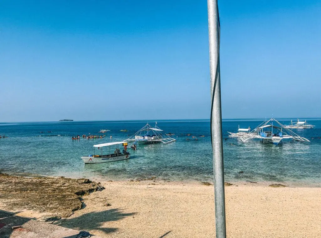 Moalboal shoreline with boats and snorkelers near Panagsama Beach